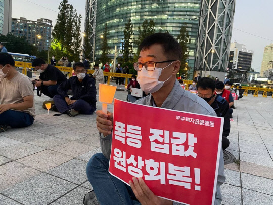 지난 13일 서울 종로구 일대에서 열린 1차 촛불집회에서 한 시민이 정부의 부동산 정책을 비판하는 손팻말을 들고 있다. <무주택자 공동행동 제공>